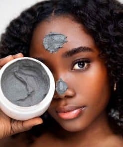 Modèle appliquant le Masque Argile Pureté & Éclat Mimiastou-Glow-Skin sur le visage, avec le pot de masque à l'argile gris foncé.